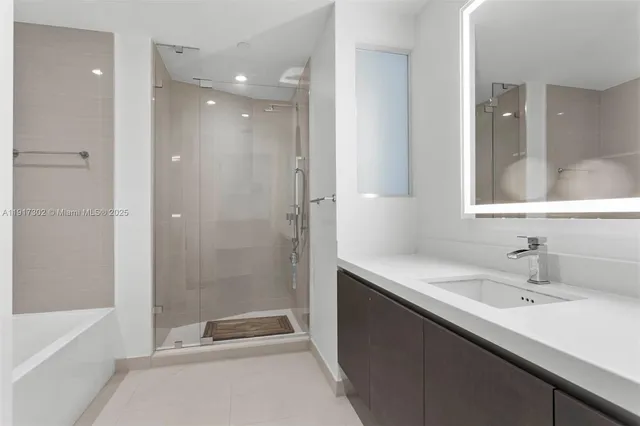 a bathroom with a bathtub shower sink vanity and mirror