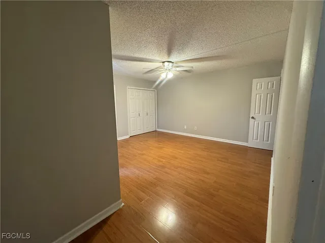 en empty room with wooden floor and fan