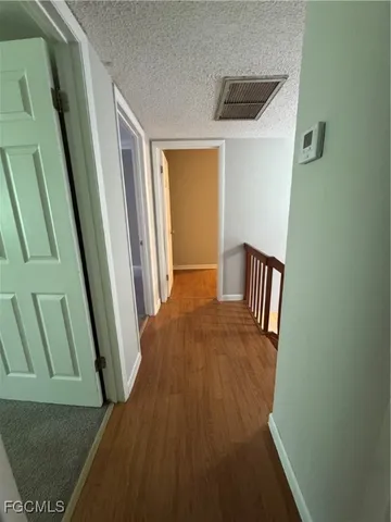 a view of a hallway with wooden floor and stairs