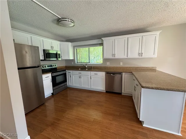 a kitchen with stainless steel appliances granite countertop a stove top oven a sink and dishwasher a refrigerator with wooden floor