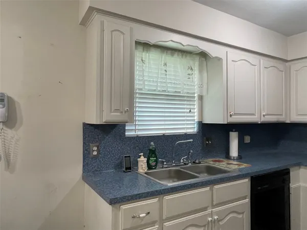 a kitchen with granite countertop a sink and a white cabinets