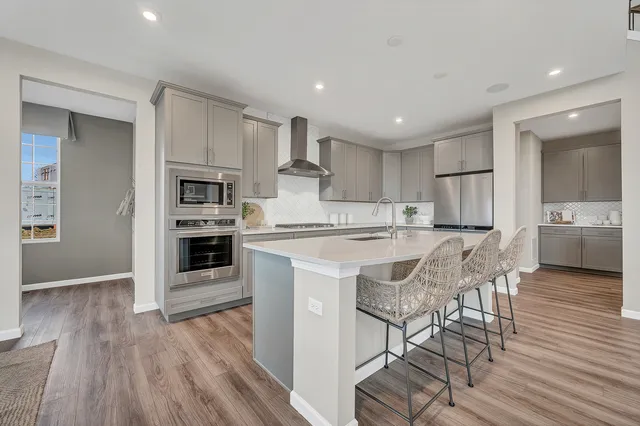 a kitchen with stainless steel appliances granite countertop a stove top oven a sink dishwasher and a refrigerator with wooden floor