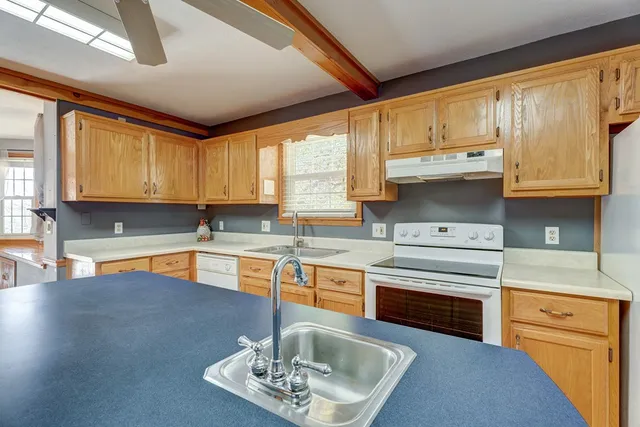 a kitchen with stainless steel appliances granite countertop wooden cabinets a sink a stove a dining table and chairs
