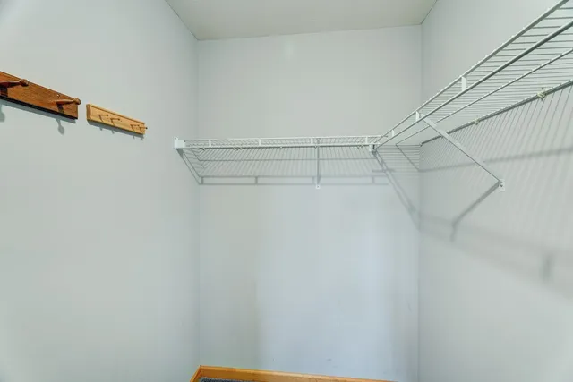 an empty room with chandelier fan and windows