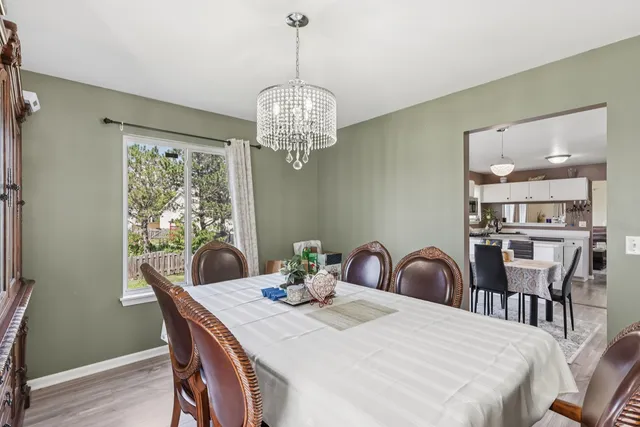 a dining room with furniture a chandelier and wooden floor