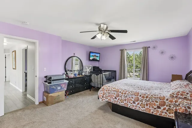 a spacious bedroom with a bed a chandelier and dresser