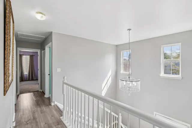 a view of a hallway with wooden floor and chandelier