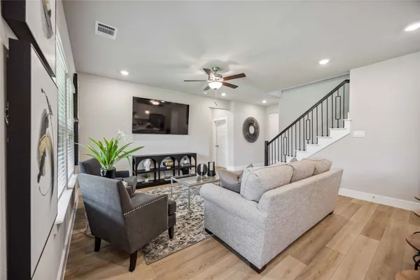 a living room with furniture ceiling fan and a flat screen tv