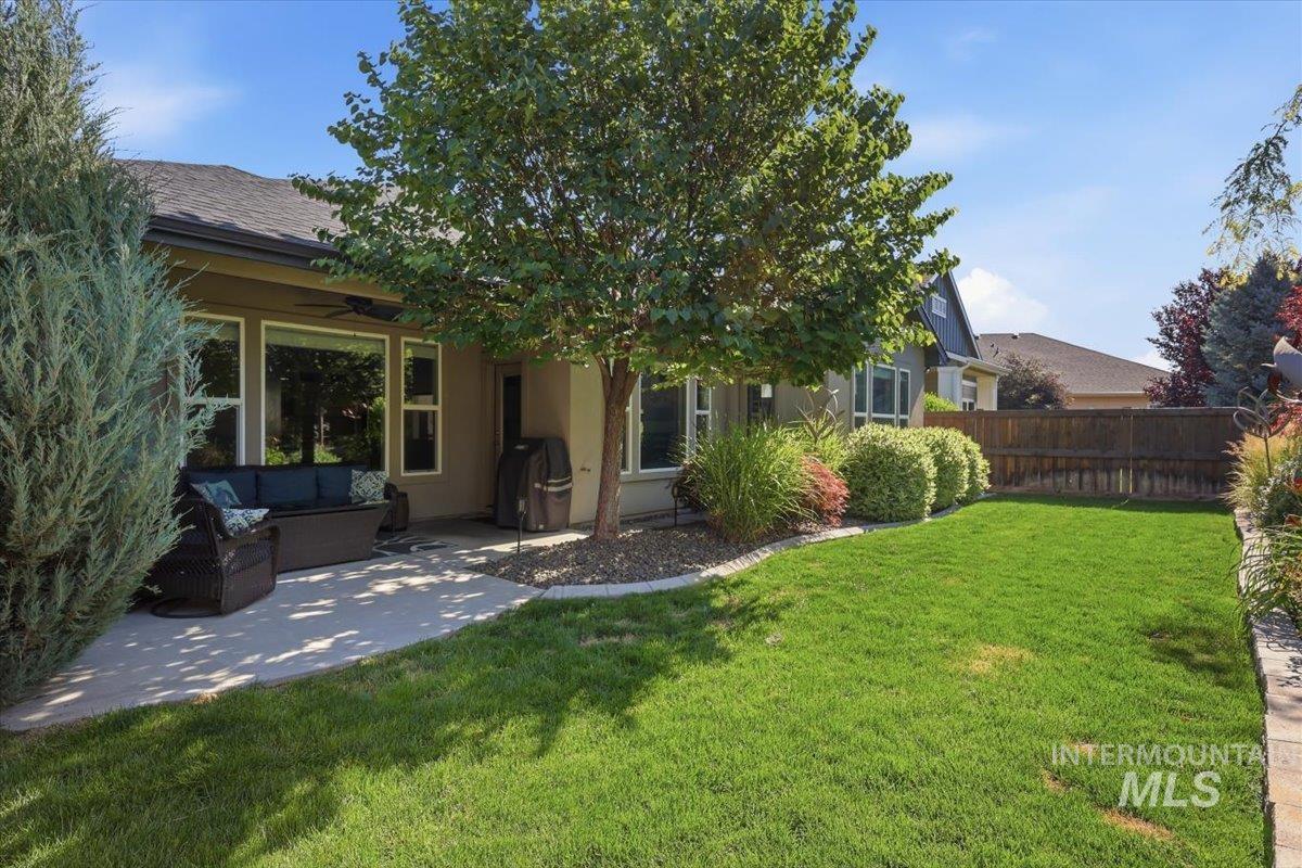 1303 West Brando Street Meridian, ID 83646 - Photo 36 of 49 Expansive backyard featuring a large concrete patio, established landscaping, mature trees, and a wooden privacy fence