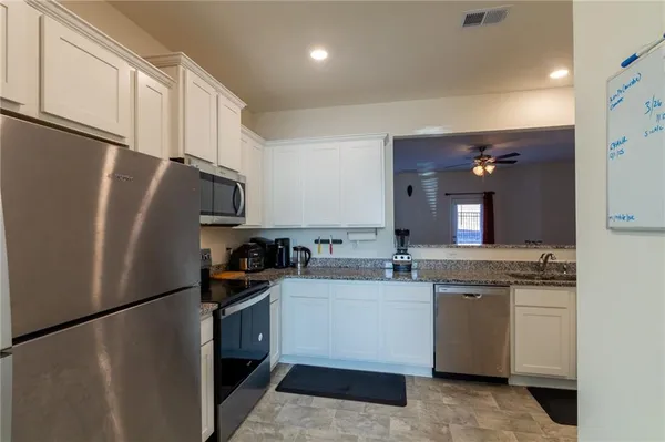 a kitchen with stainless steel appliances a refrigerator a sink and white cabinets