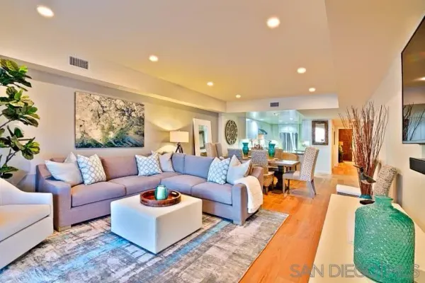 a living room with furniture kitchen view and a large window