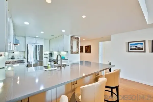 a room with stainless steel appliances kitchen island granite countertop a table chairs and a refrigerator