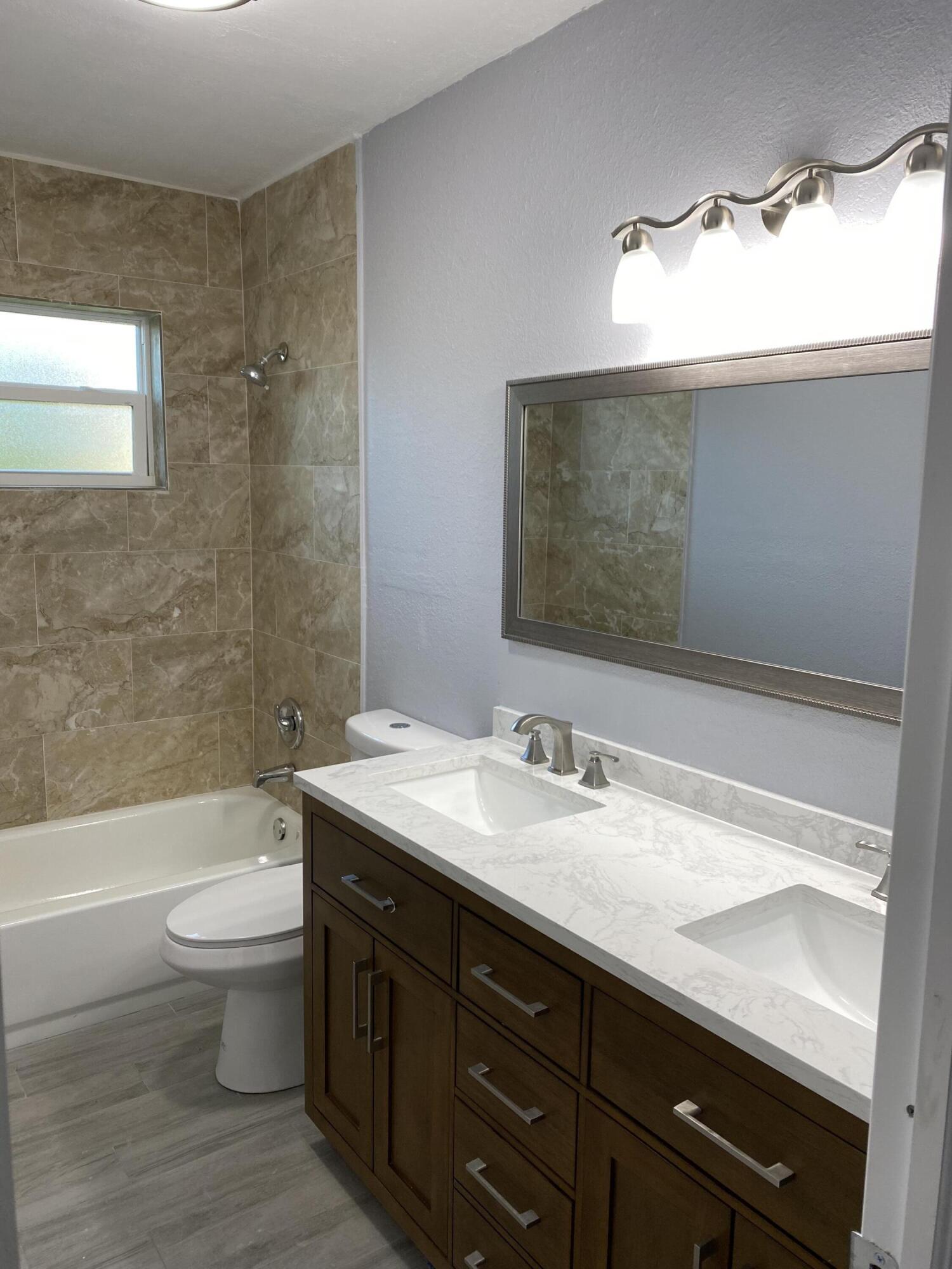 232 Northwest 9th Street Pompano Beach, FL 33060 - Photo 11 of 46 a bathroom with a double vanity sink toilet and a mirror