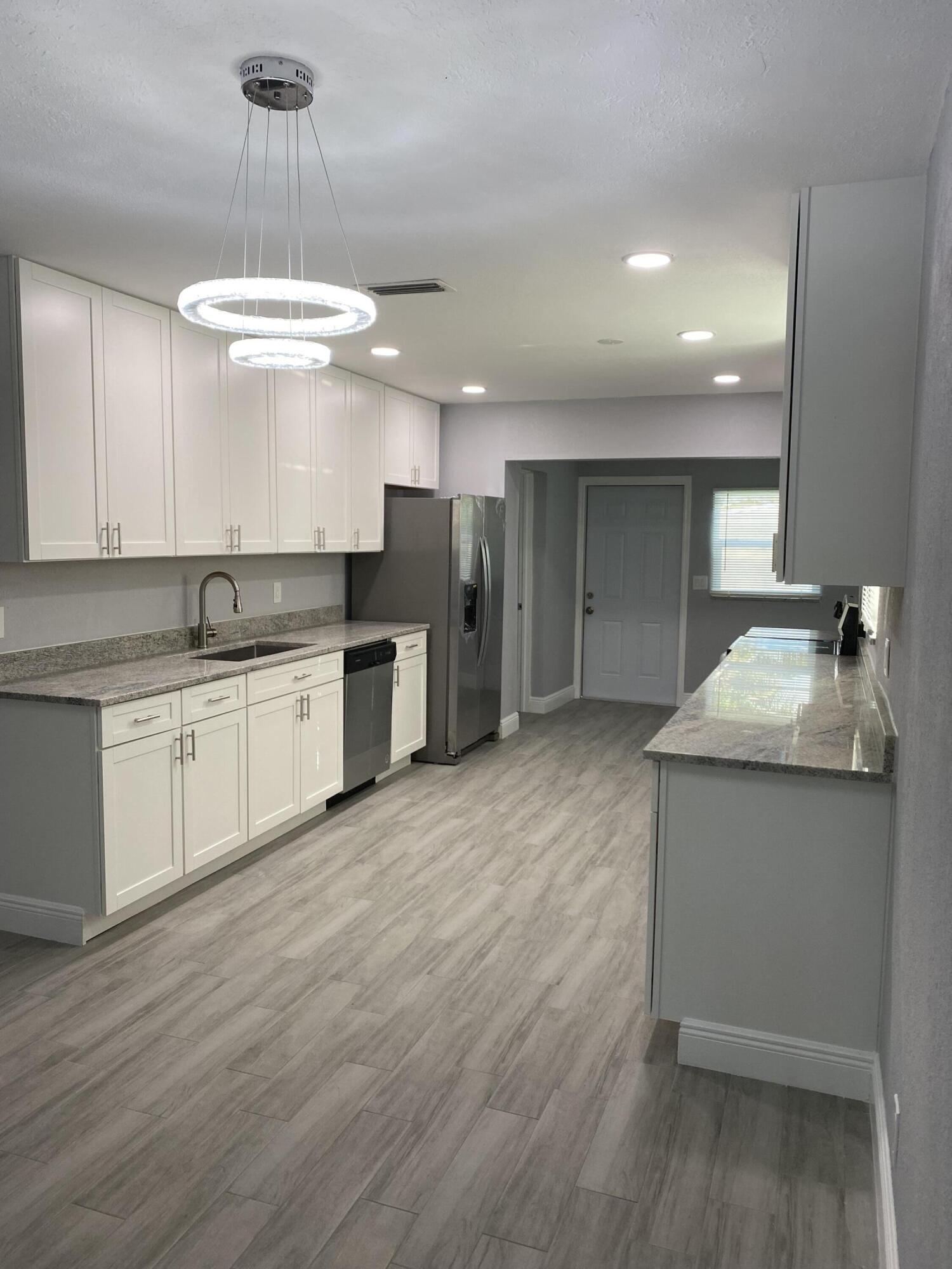 232 Northwest 9th Street Pompano Beach, FL 33060 - Photo 32 of 46 a kitchen with stainless steel appliances granite countertop a sink a stove a refrigerator and island with wooden floor