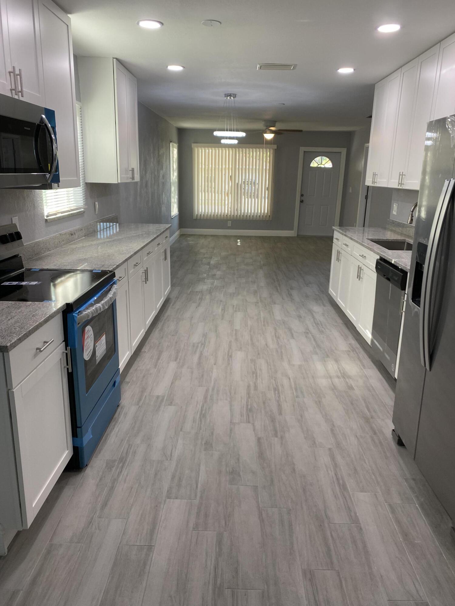232 Northwest 9th Street Pompano Beach, FL 33060 - Photo 39 of 46 a large kitchen with stainless steel appliances granite countertop a large stove a sink dishwasher and a refrigerator with wooden floor