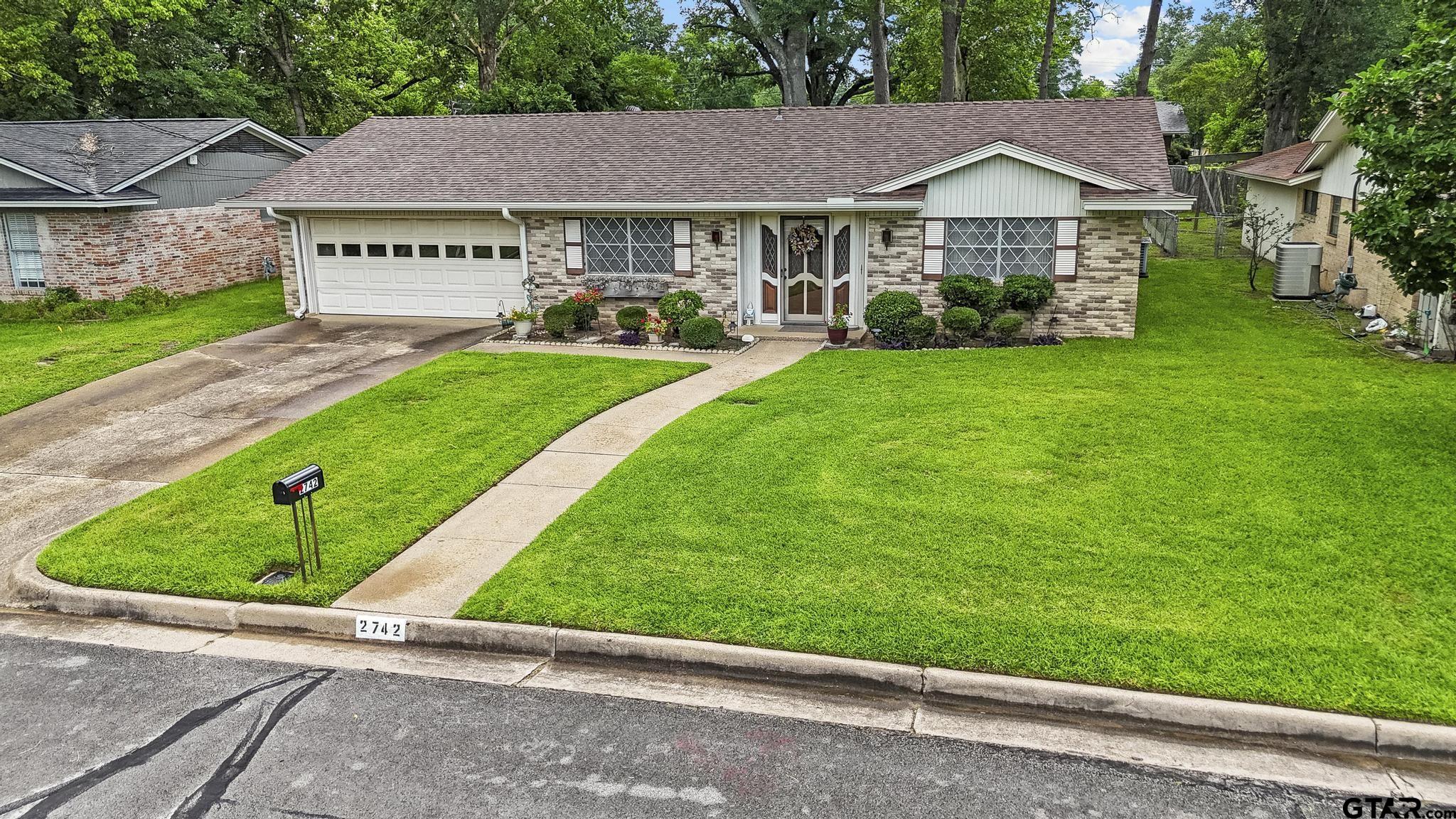 2742 Lisa Lane Tyler, TX 75701 - Photo 32 of 32 a front view of a house with a yard and garage