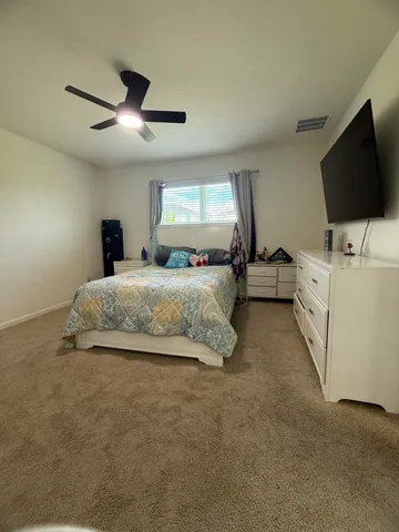 a spacious bedroom with a bed and a flat screen tv