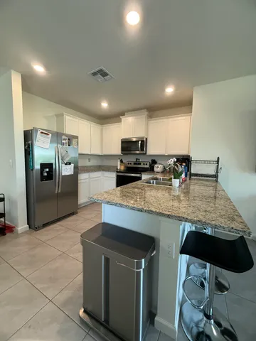 a kitchen with granite countertop a sink a counter top space stainless steel appliances and cabinets