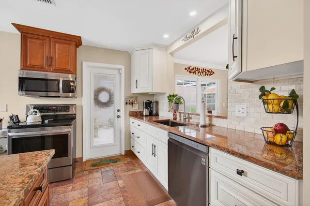 a kitchen with stainless steel appliances granite countertop a sink and cabinets