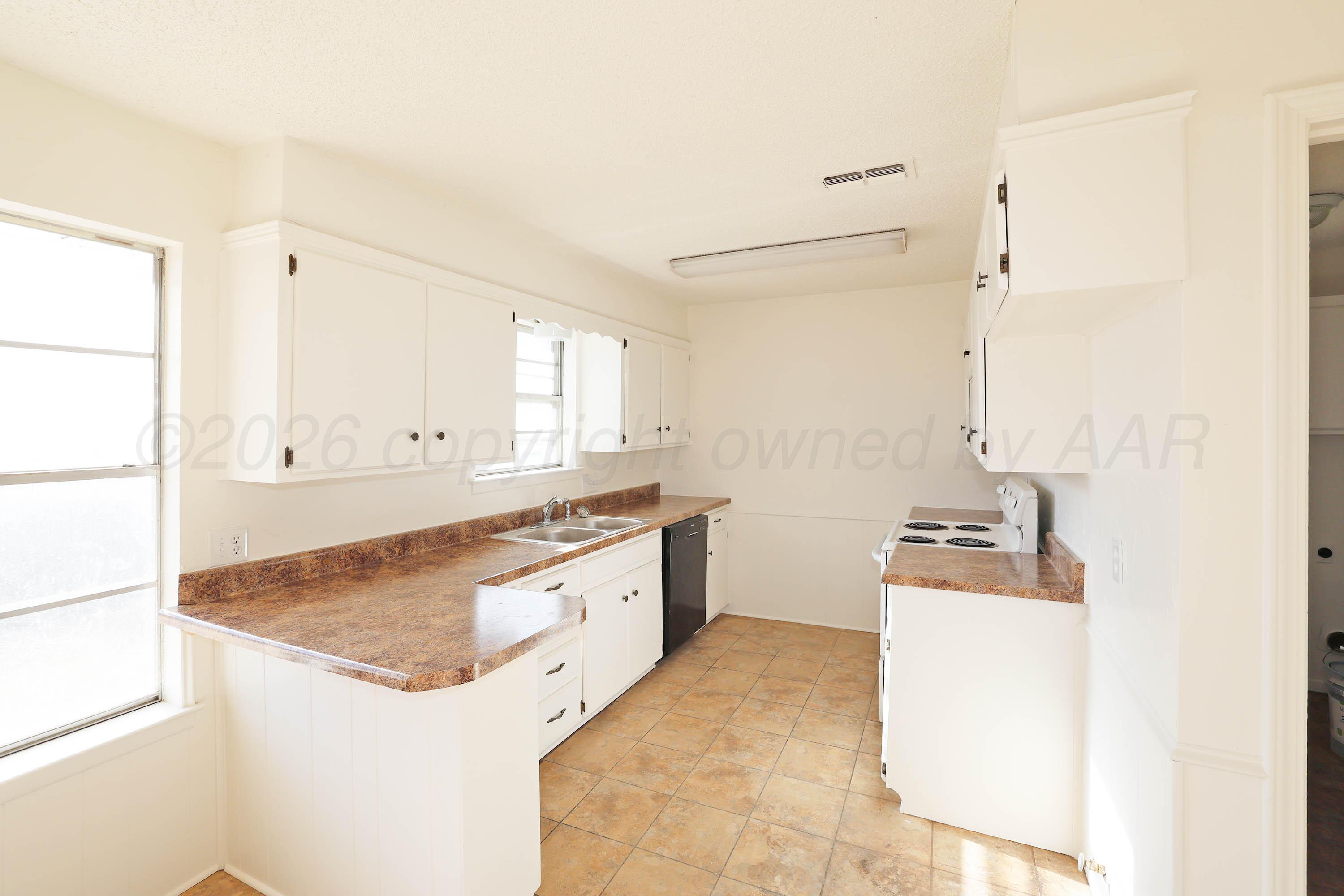 4415 Kingston Road Amarillo, TX 79109 - Photo 7 of 28 a kitchen with a sink stove and wooden cabinets