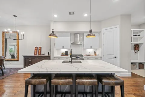a kitchen with a dining table chairs and wooden floor