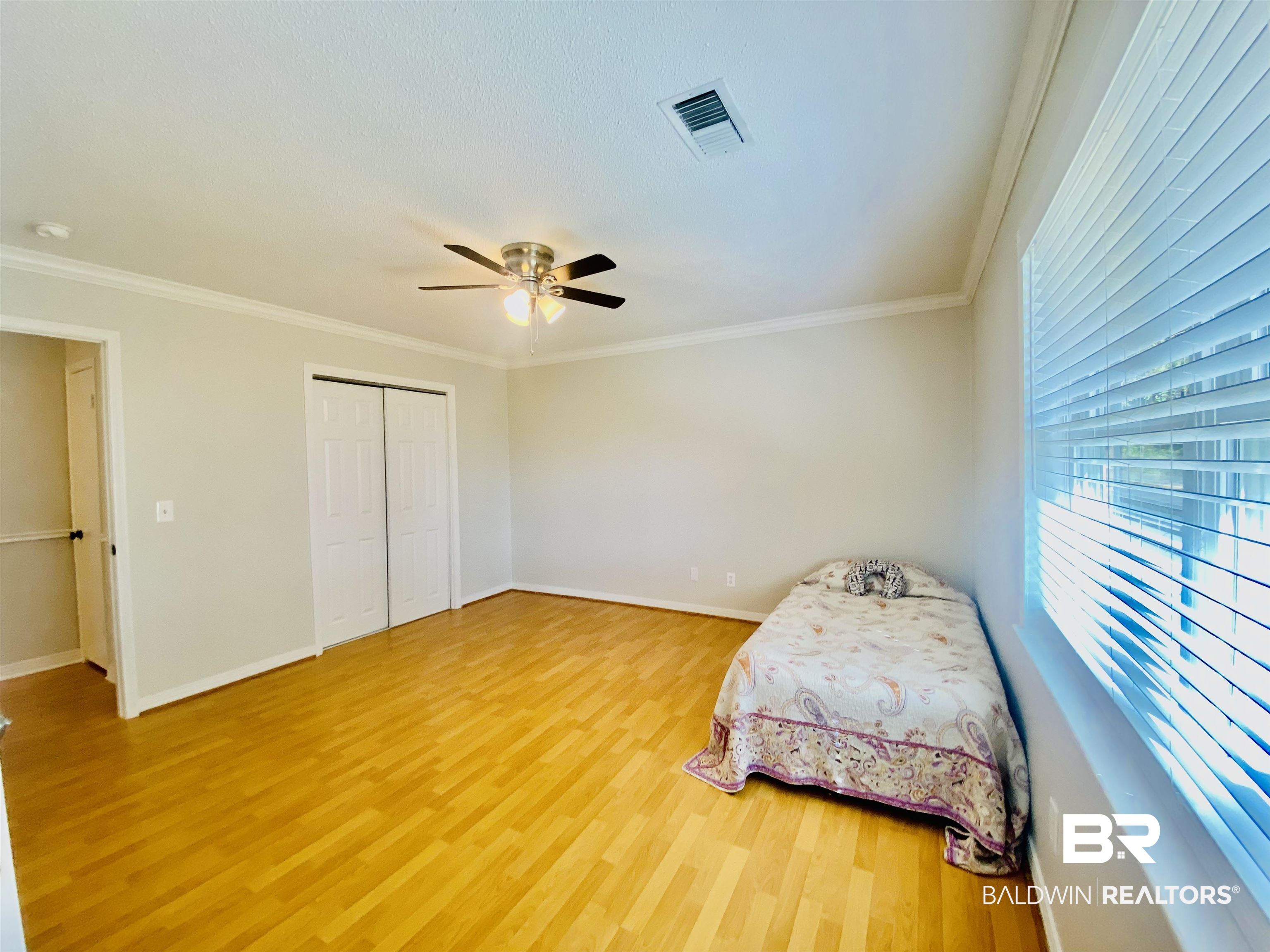 265 Azalea Drive Monroeville, AL 36460 - Photo 23 of 39 Unfurnished bedroom with wood-type flooring, ceiling fan, crown molding, and a closet