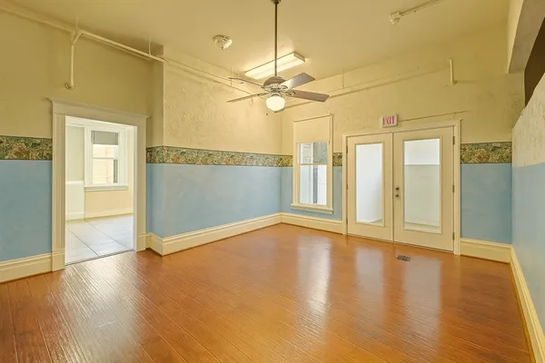 a view of an empty room with wooden floor and a window