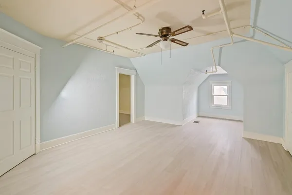 an empty room with a fan & a window