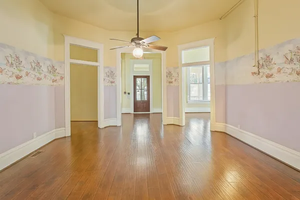 a view of an empty room with wooden floor and a window