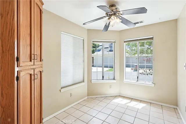 a view of an empty room with window and chandelier fan