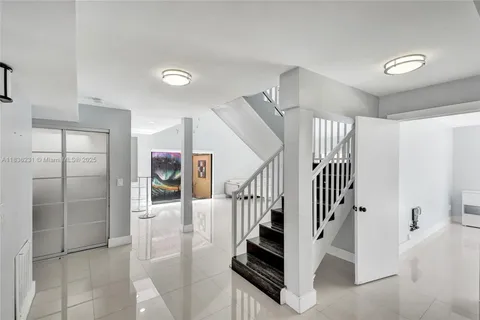 a view of a livingroom with a flesh screen tv and stairs