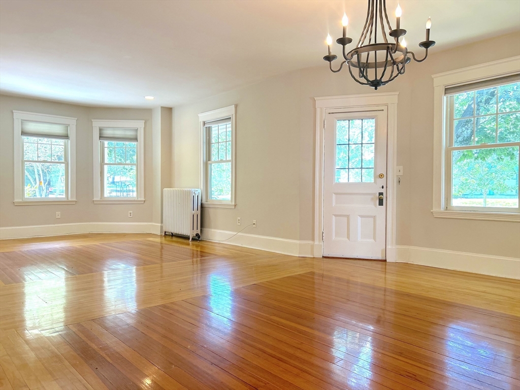 59 Ackers Avenue, Unit 1 Brookline, MA 02445 - Photo 2 of 13 a view of an empty room with wooden floor and a window