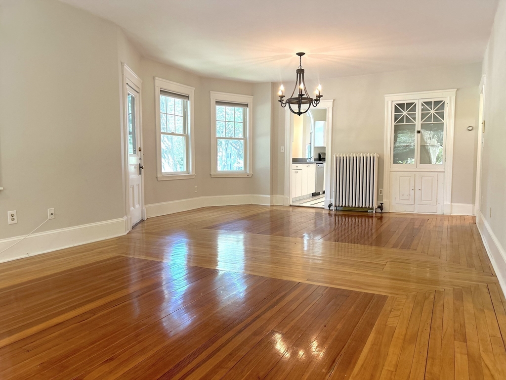 59 Ackers Avenue, Unit 1 Brookline, MA 02445 - Photo 4 of 13 an empty room with wooden floor and windows