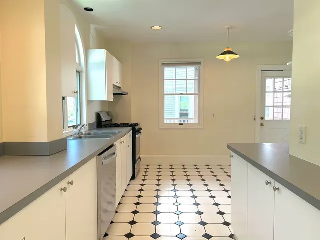 a kitchen with granite countertop a sink a stove a window and cabinets