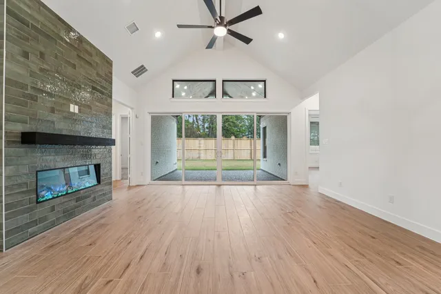 an empty room with wooden floor fireplace and windows