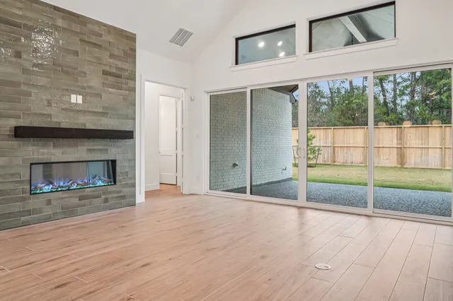 a view of an empty room with wooden floor and a fireplace