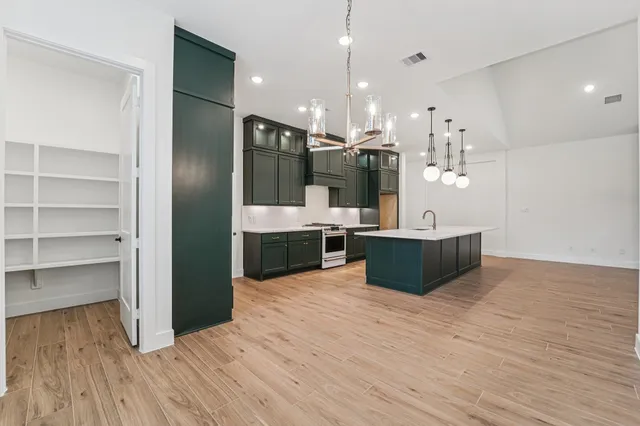 a large kitchen with stainless steel appliances kitchen island a large counter top and a wooden floors