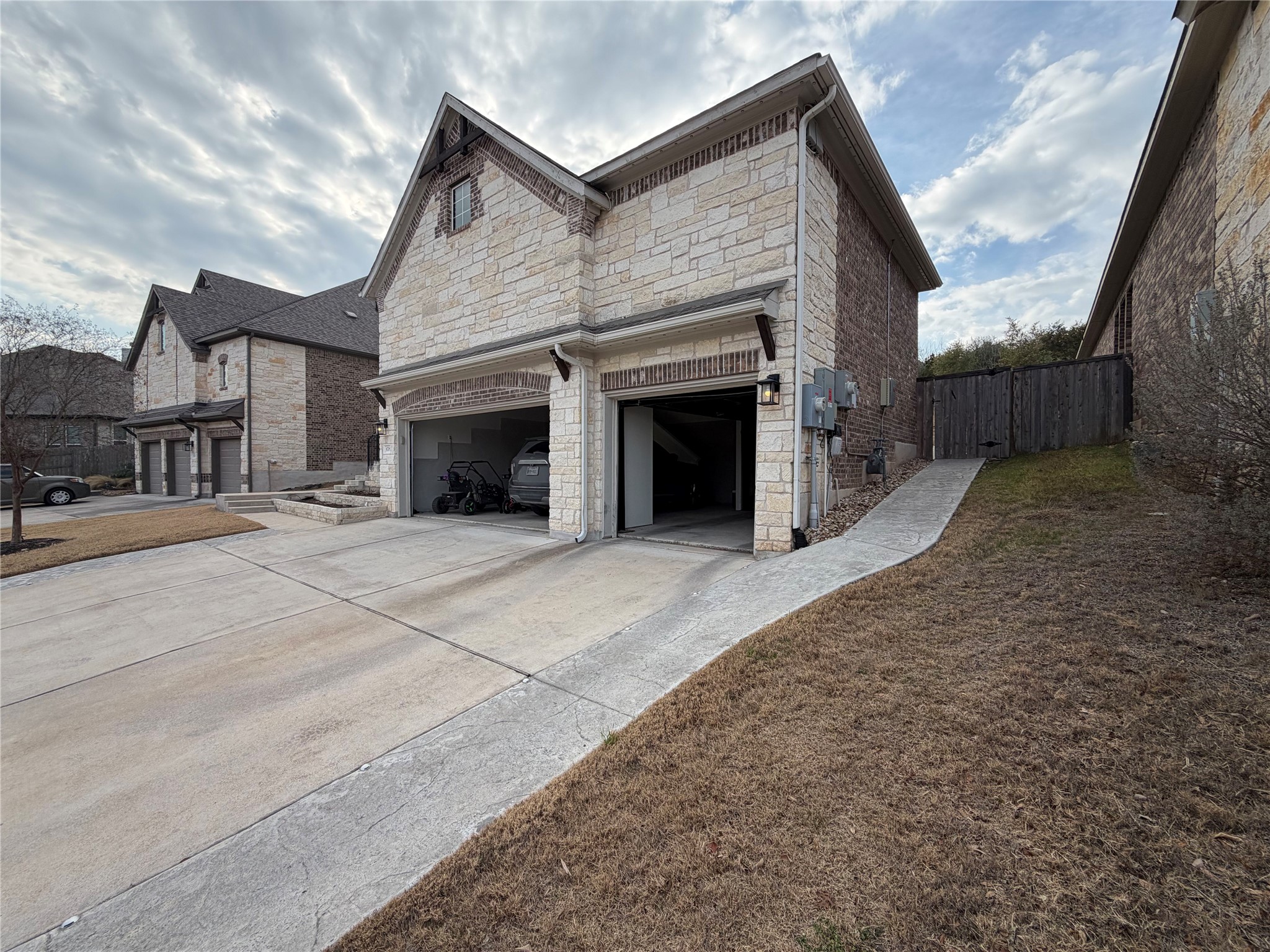8709 Moccasin Path Austin, TX 78736 - Photo 31 of 34 View of property exterior featuring stone siding, driveway, a garage, and a gate
