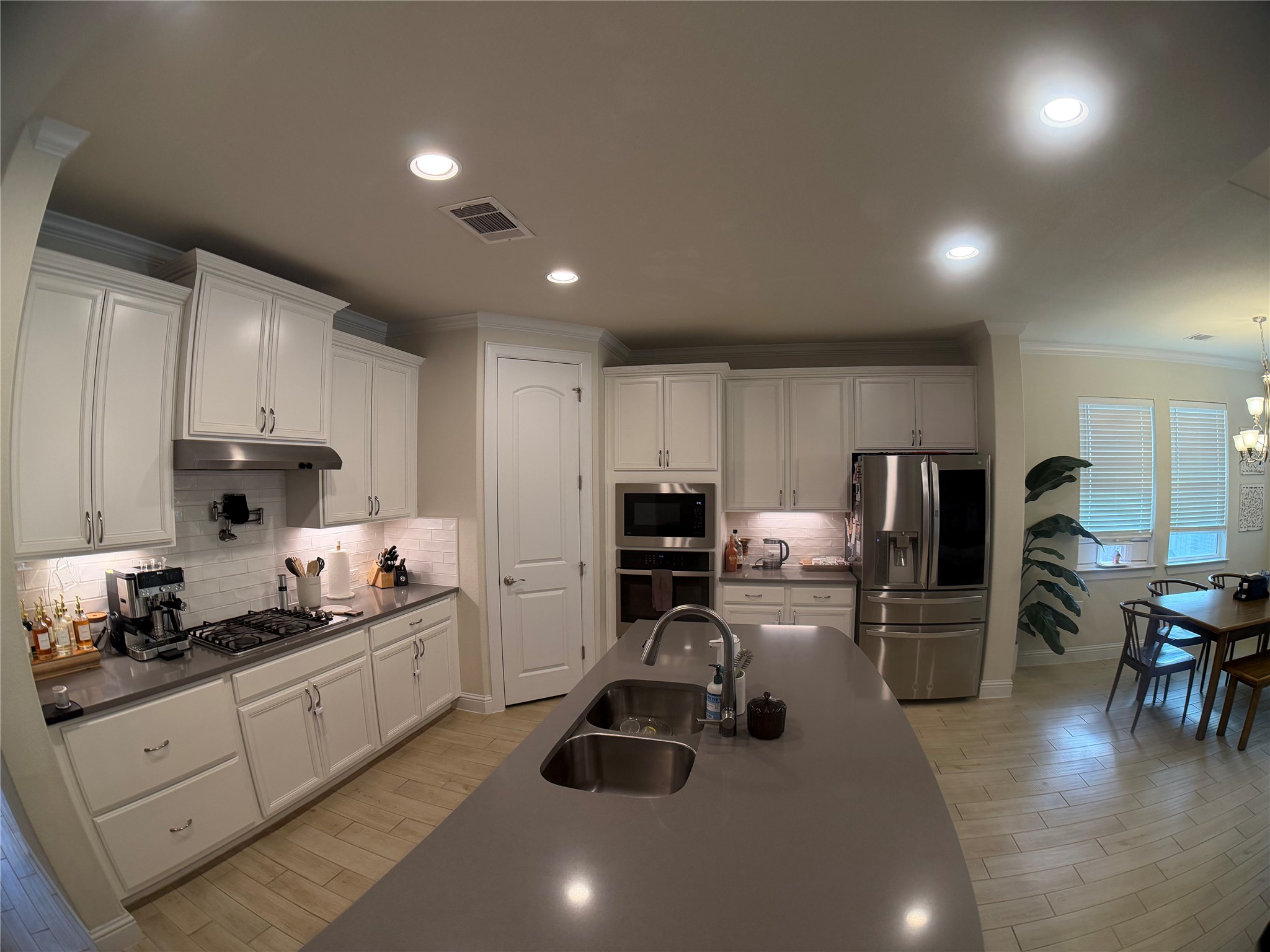 8709 Moccasin Path Austin, TX 78736 - Photo 7 of 34 Kitchen featuring stainless steel appliances, ornamental molding, wood finish floors, and white cabinetry