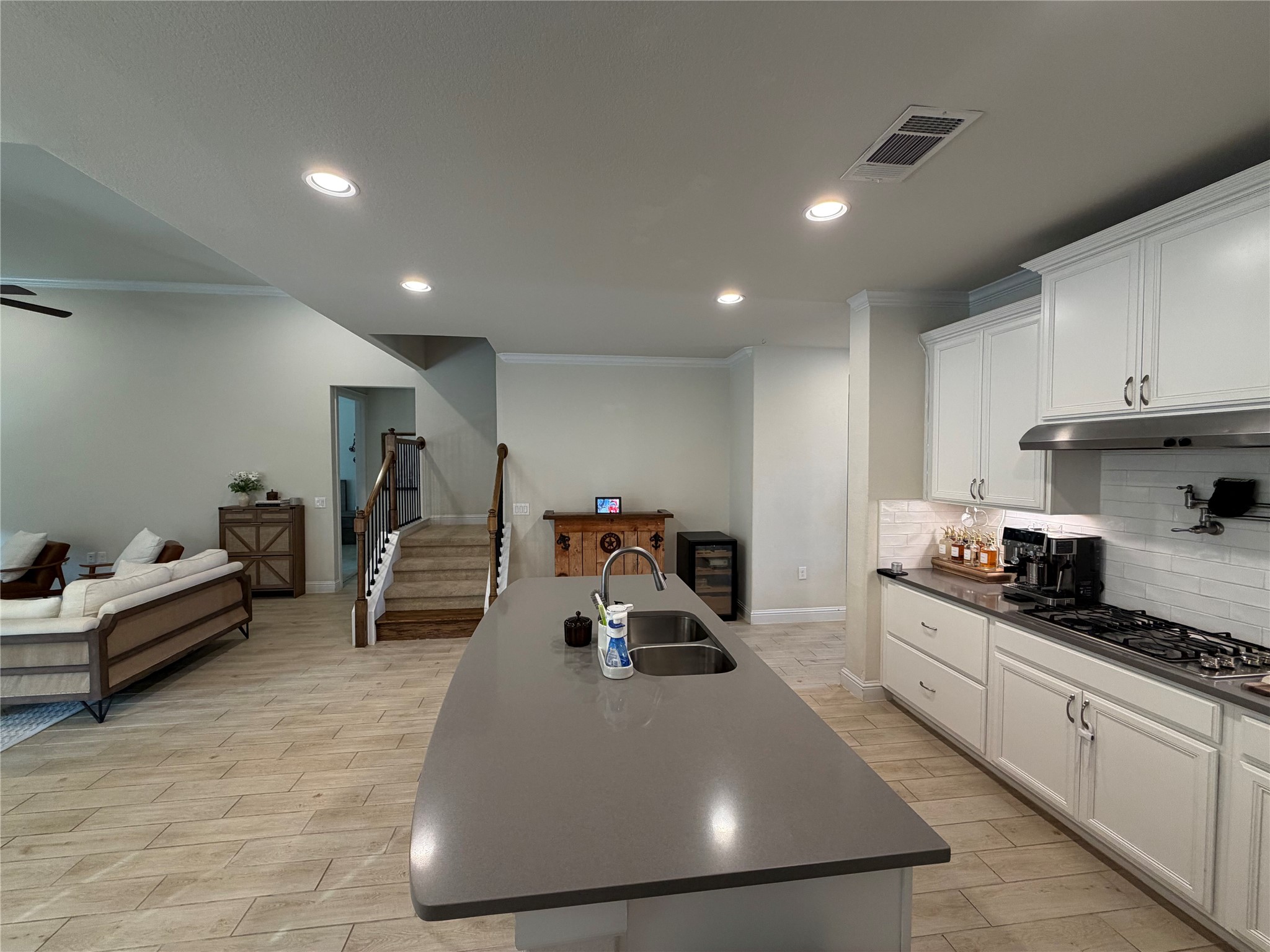8709 Moccasin Path Austin, TX 78736 - Photo 34 of 34 Kitchen with crown molding, wood tiled floors, white cabinets, open floor plan, and stainless steel gas cooktop