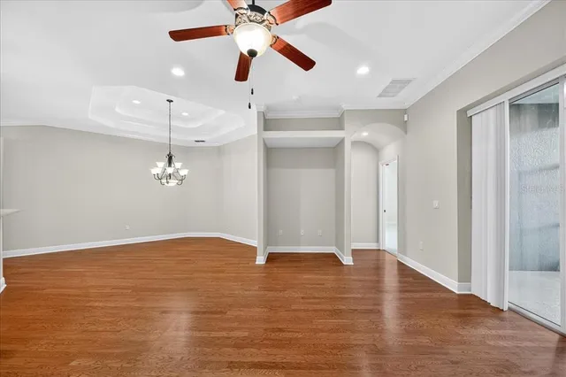 wooden floor in an empty room with a chandelier fan