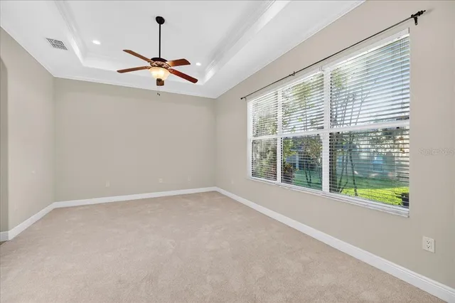 an empty room with windows and ceiling fan