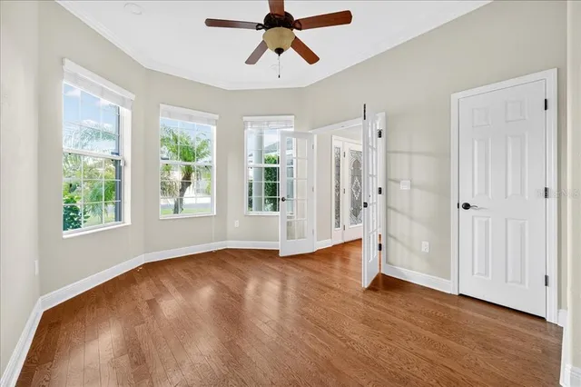 a view of empty room with wooden floor and fan
