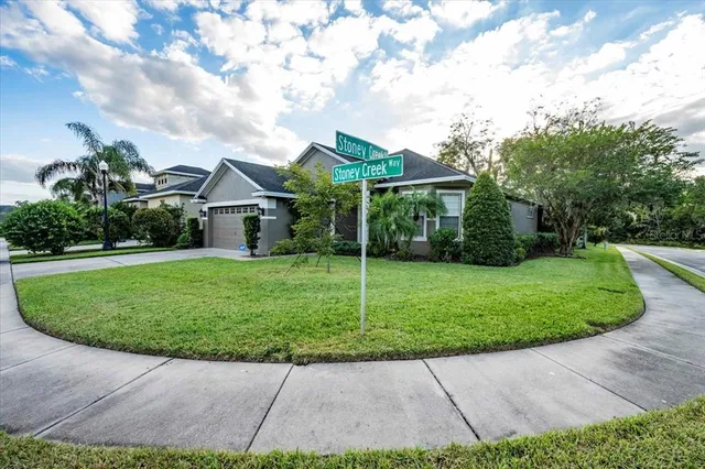 a view of a house with a big yard plants and large trees