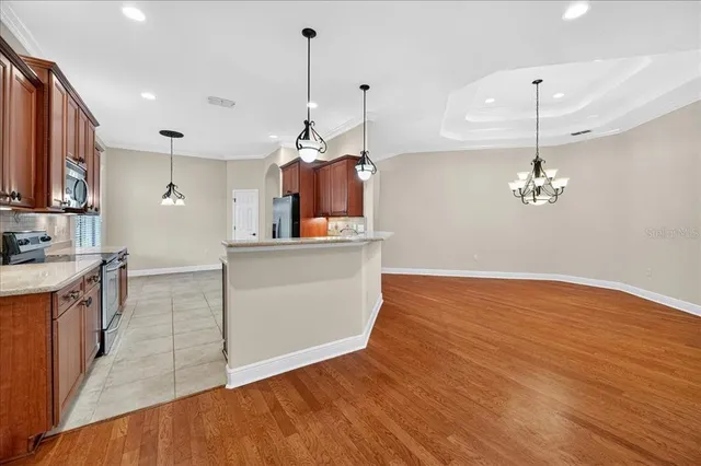 a kitchen with stainless steel appliances granite countertop a sink a stove a refrigerator and island with wooden floor