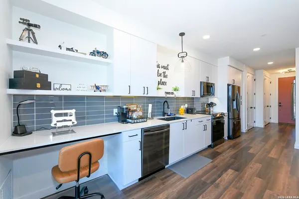 a kitchen with stainless steel appliances granite countertop a refrigerator a sink dishwasher a stove and white countertops with wooden floor
