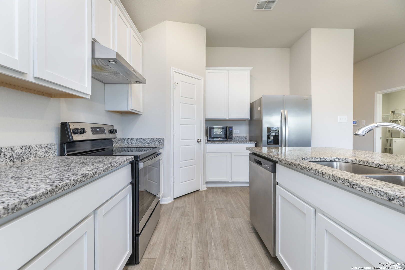 765 Stonemanor Bay Seguin, TX 78155 - Photo 2 of 29 a kitchen with a sink dishwasher a refrigerator a stove and white cabinets with wooden floor