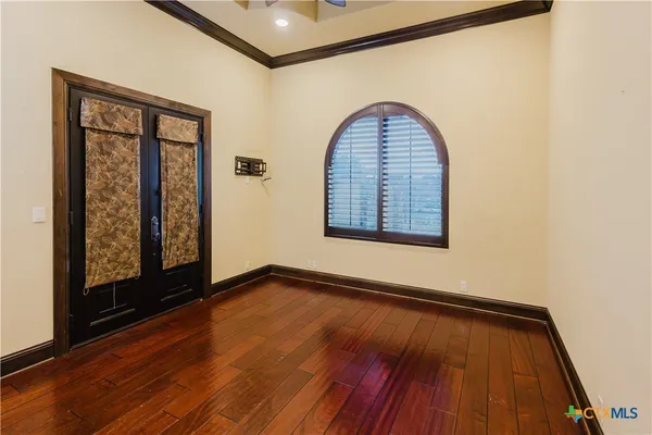 a view of an empty room with wooden floor and a window