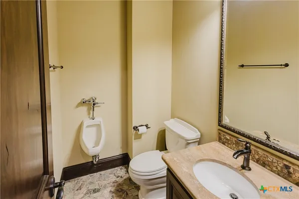 a bathroom with a granite countertop toilet and a sink