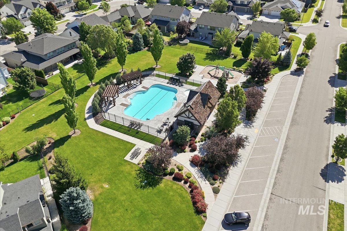 1303 West Brando Street Meridian, ID 83646 - Photo 47 of 49 Community amenities featuring a fenced swimming pool, adjacent clubhouse with gabled roof, and playground area, all surrounded by manicured green spaces and mature trees